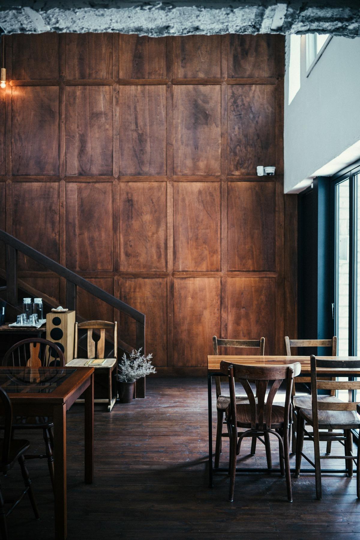 Mesas de madera junto al ventanal en un salón de techos altos